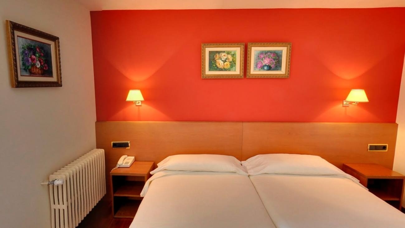 a hotel room with two beds and two paintings on the wall