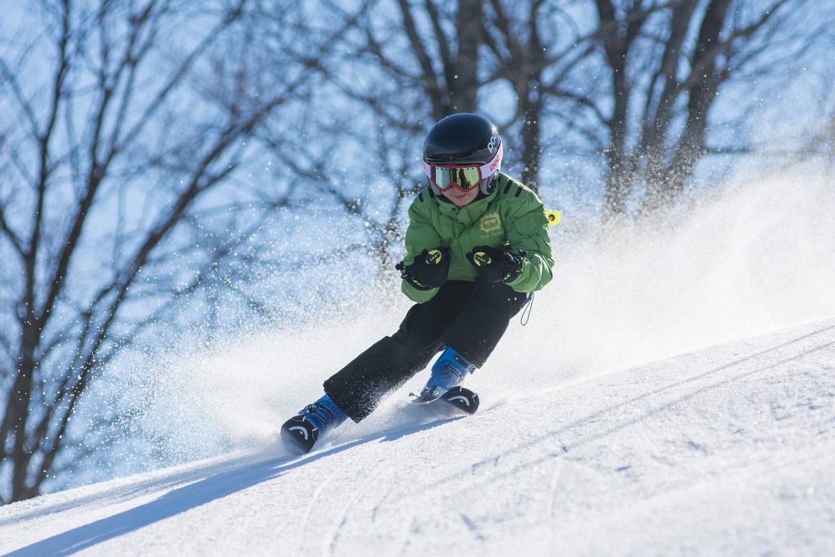 a person skiing down a snowy hill with a green jacket that says ' alpine ' on it