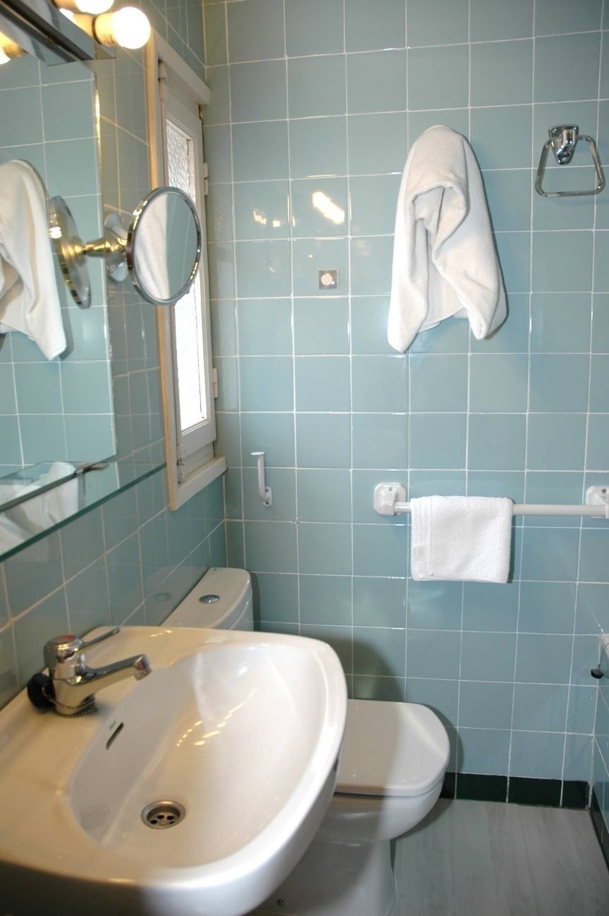 a bathroom with blue tiles and a sink and toilet