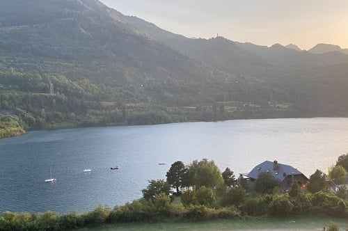 un lago rodeado de montañas y árboles con algunos botes en el agua