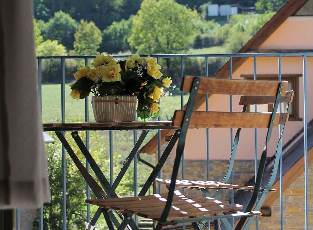un balcon avec une table et une chaise en bois et un pot de fleurs