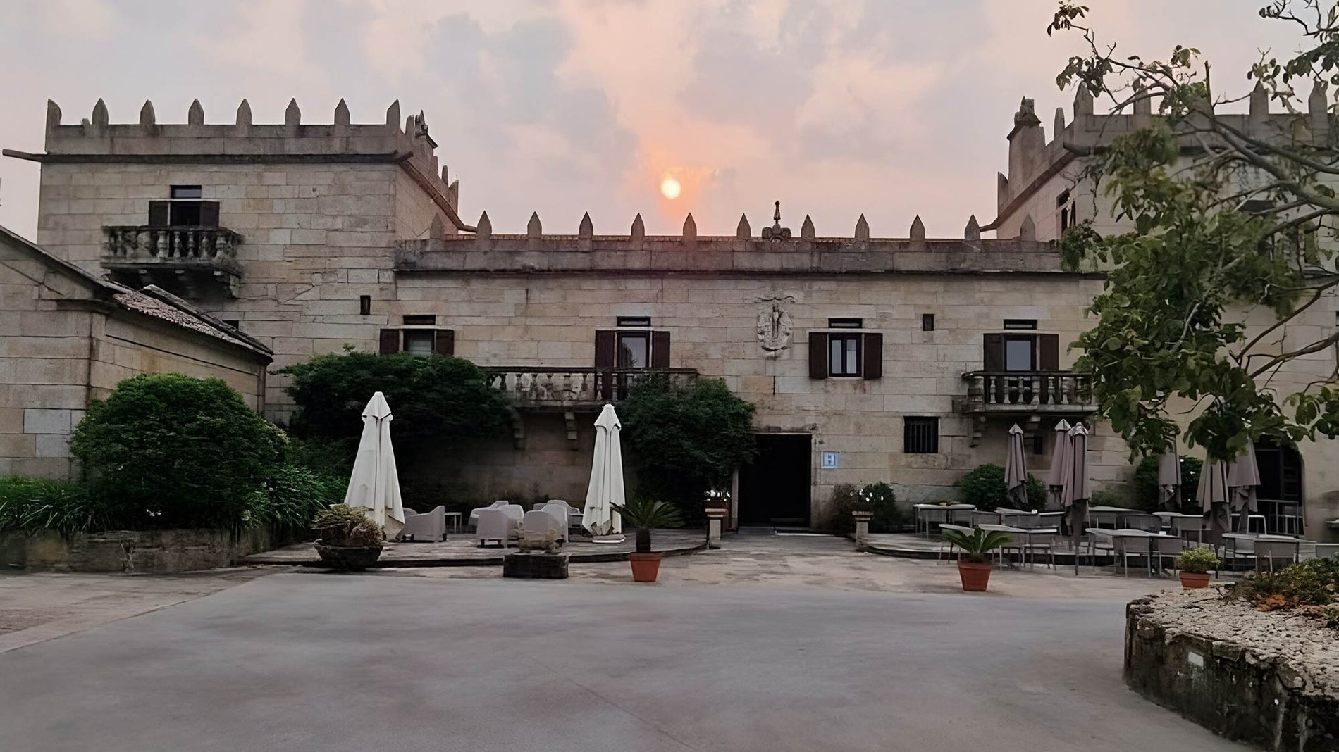 un edificio de piedra con un techo de tejas está rodeado de palmeras