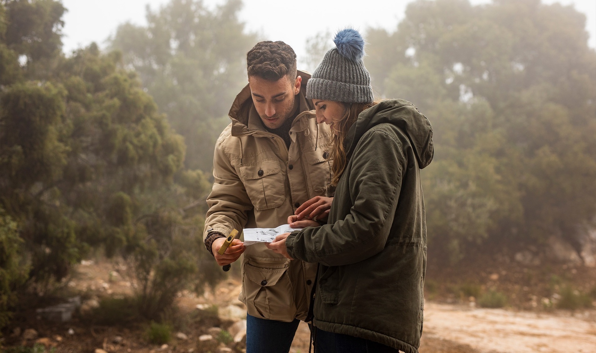 un homme et une femme regardent une carte dans une forêt