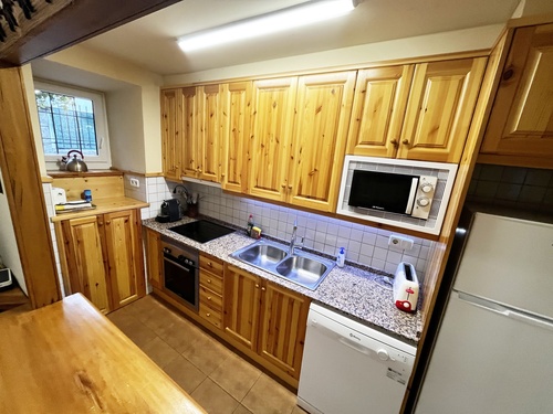 Cette cuisine chaleureuse présente des armoires en bois clair, un comptoir en granit et une variété d'appareils électroménagers.