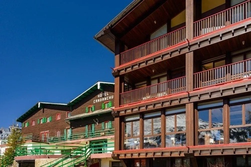 un edificio de madera con balcones rojos y verdes y la palabra hotel encima