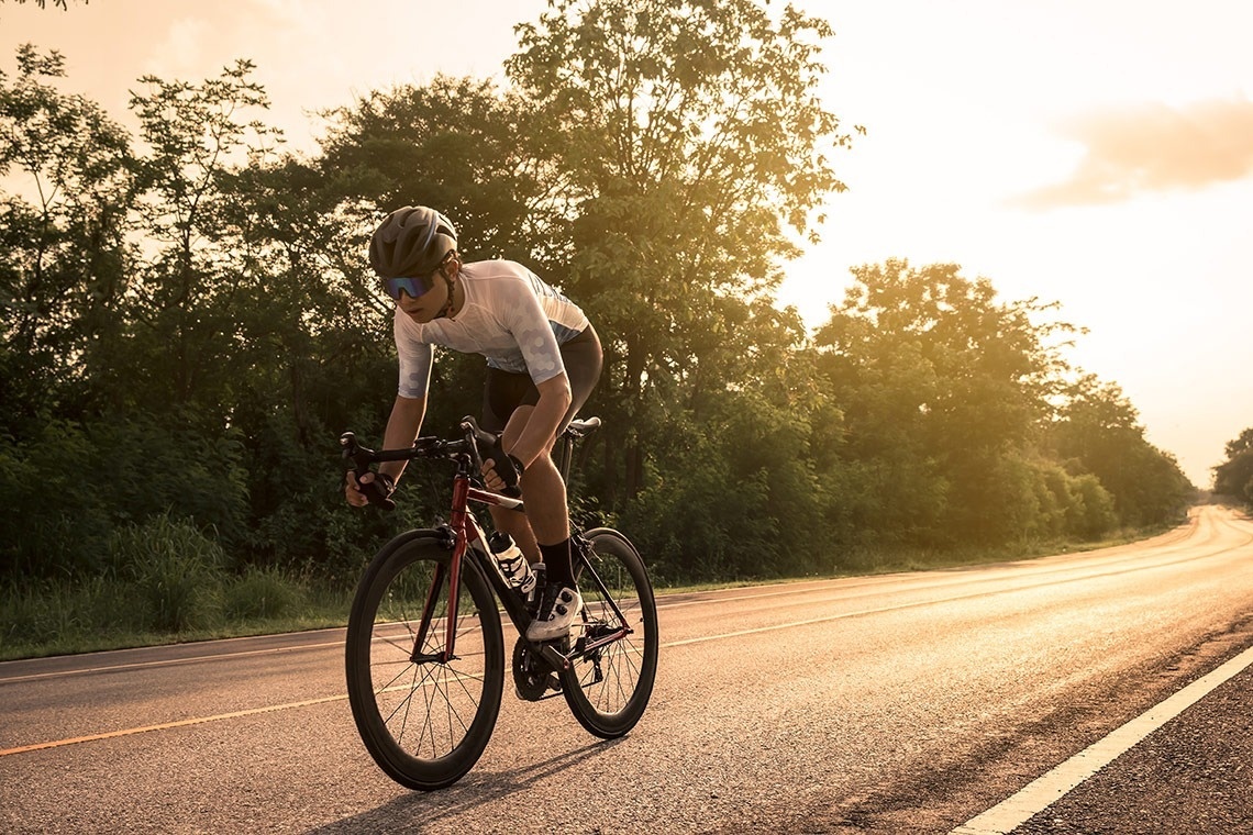 un hombre con un casco y gafas de sol monta una bicicleta en la carretera
