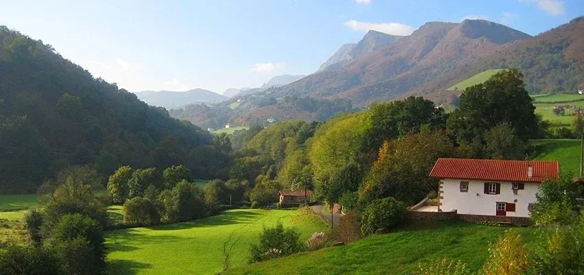 Finca rural enSNO: Corporativa, rodeada de montañas y exuberante vegetación, con casa de tejado rojo.
