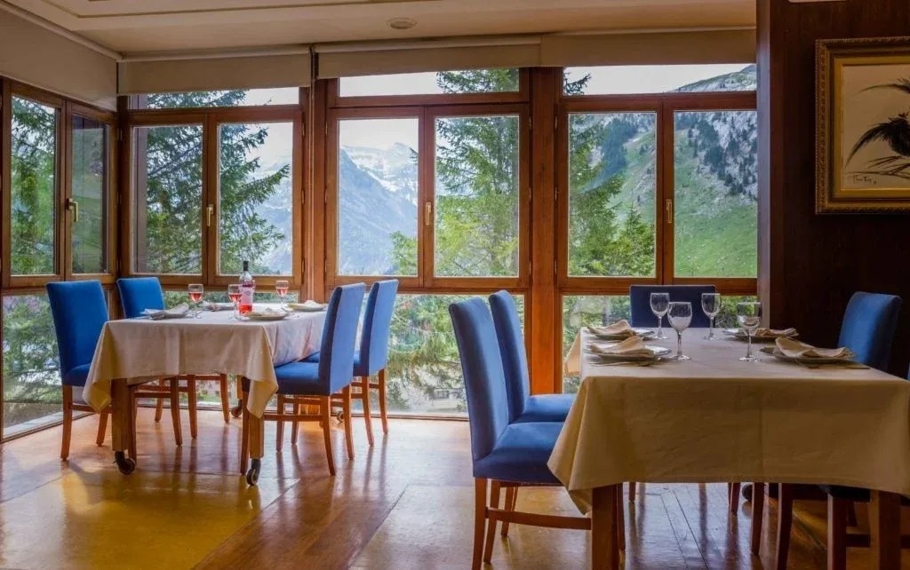 une salle à manger avec des tables et des chaises avec une vue sur les montagnes