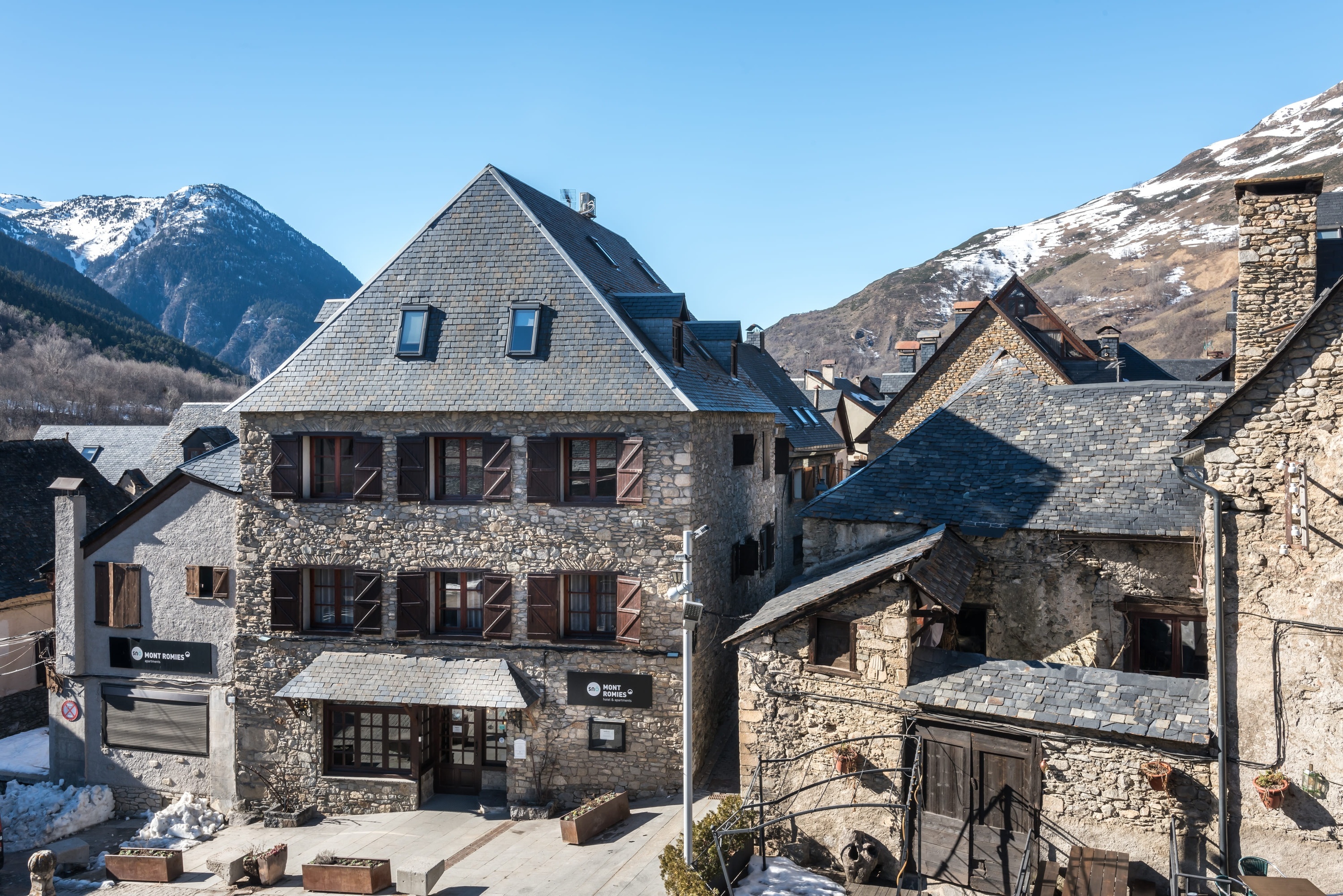 un edificio de piedra cubierto de nieve y un cartel que dice monts i bones