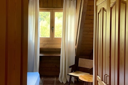 una habitación de madera con una ventana y cortinas blancas