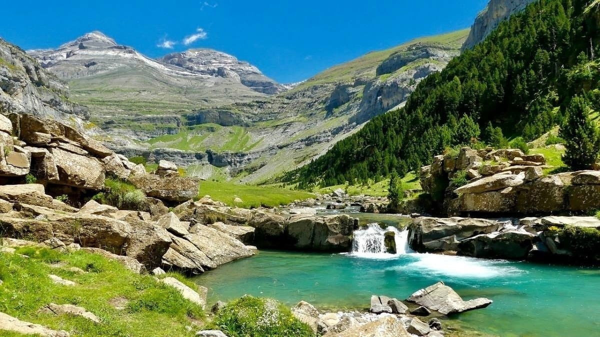 une cascade coule dans un lac entouré de rochers et de montagnes