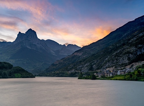 un lac entouré de montagnes au coucher du soleil