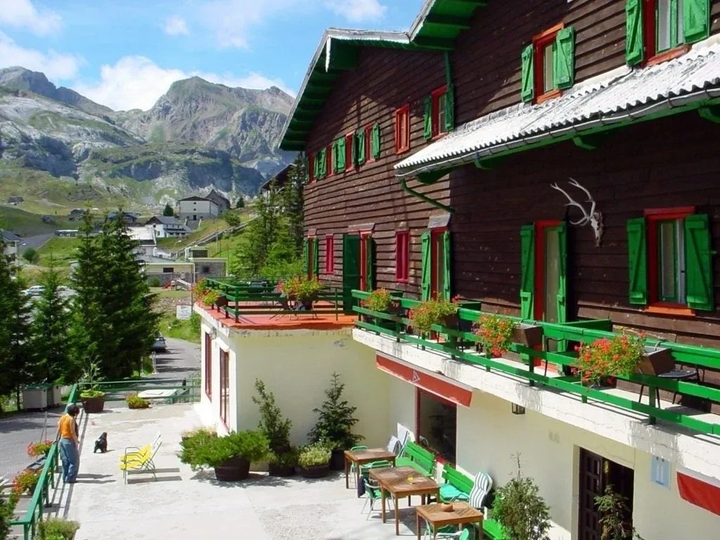 un edificio de madera con balcones verdes y una montaña en el fondo