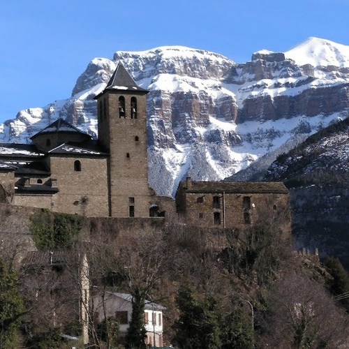 una iglesia con una torre de campana y una montaña cubierta de nieve en el fondo