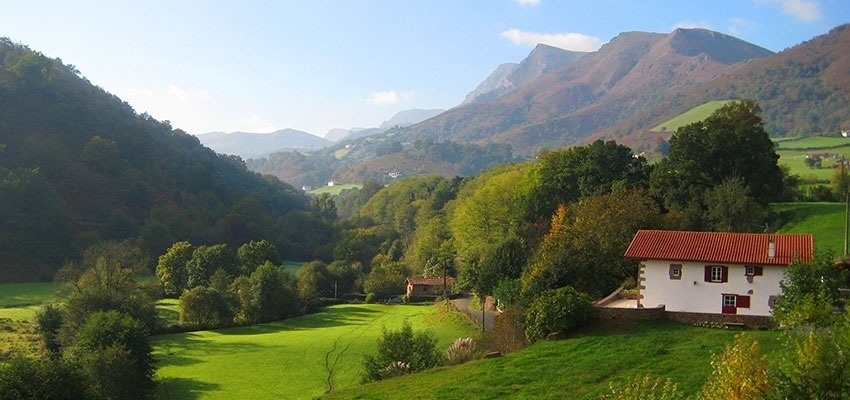 una pequeña ciudad está rodeada de montañas y árboles en otoño .