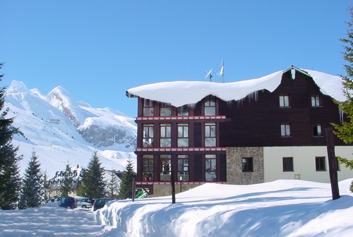 a snow covered building with mountains in the background