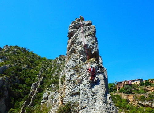 a man climbs a rocky cliff with a red rope