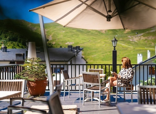 a woman sits on a balcony under an umbrella reading a book