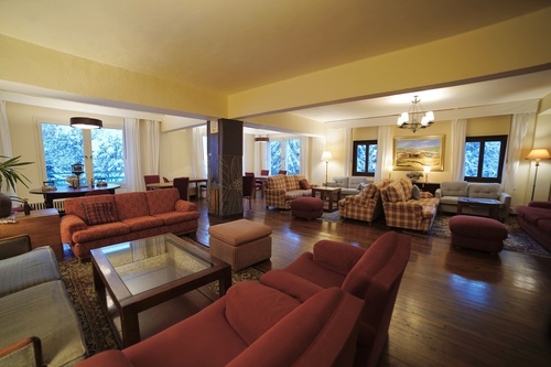 Luminoso salón de hotel con sofás confortables, suelo de madera y vistas invernales.