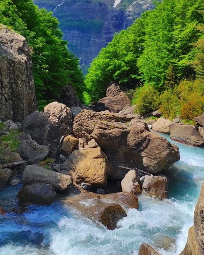 un río fluye a través de un valle lleno de rocas y árboles