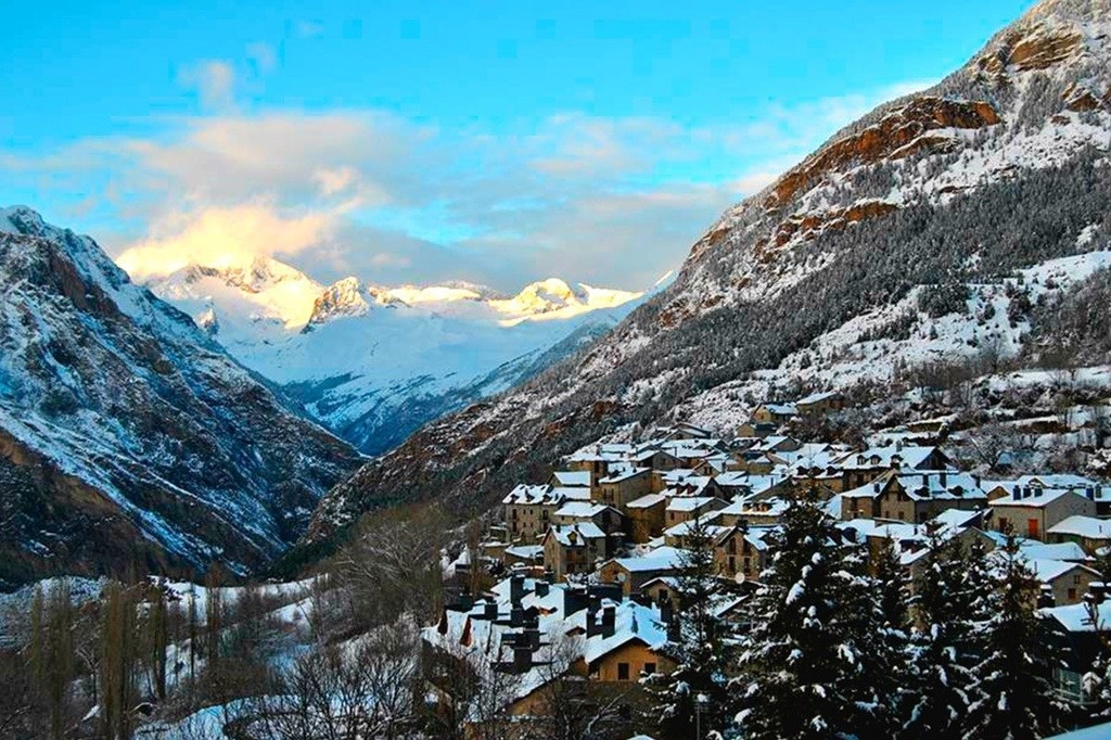 una pequeña ciudad está rodeada de montañas cubiertas de nieve