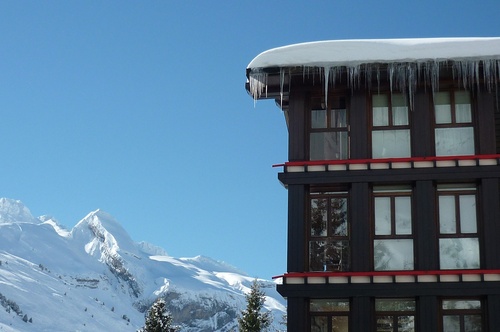 un bâtiment avec des glaçons suspendus au toit avec des montagnes en arrière-plan