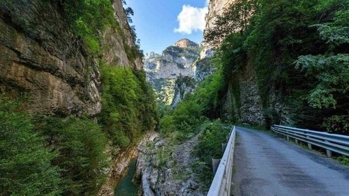 un camino que conduce a través de un cañón rodeado de montañas y árboles .