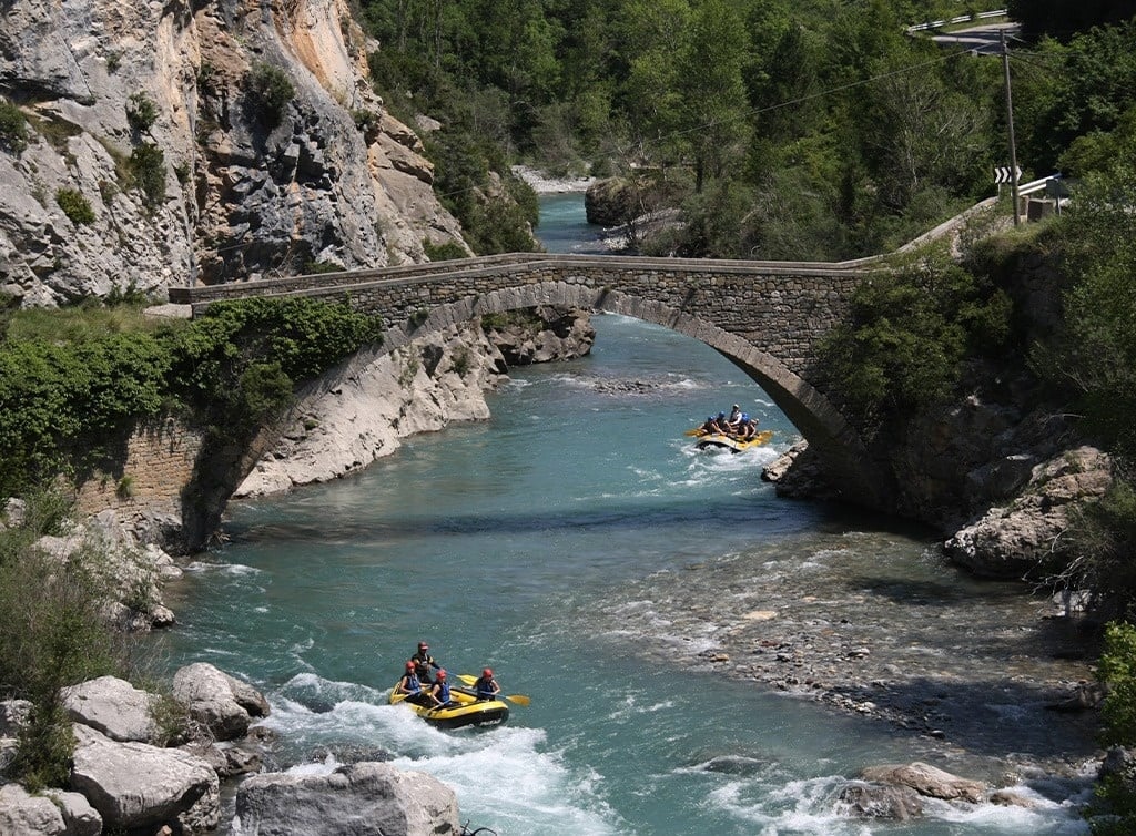 un grupo de rafting en un río con un puente en el fondo