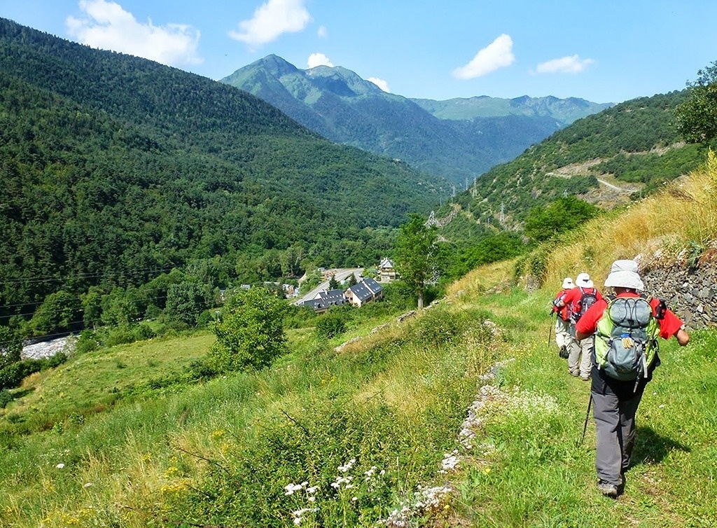 un groupe de personnes avec des sacs à dos marchent sur un sentier dans les montagnes