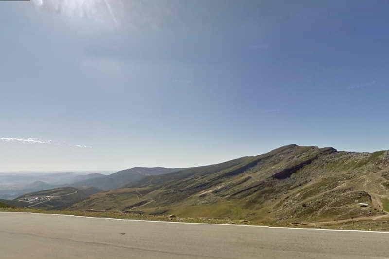 un homme fait du vélo sur une route avec des arbres en arrière-plan