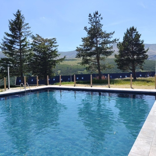 Piscina SNO: La Corza Blanca con árboles y montañas de fondo.