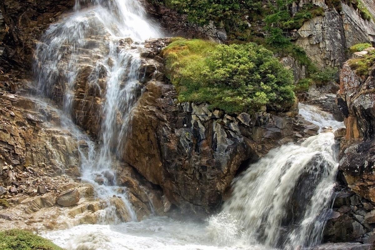 un río que fluye a través de un valle con montañas en el fondo