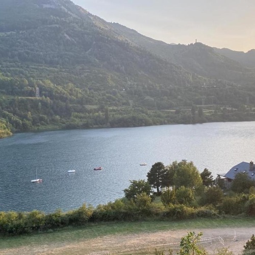 un lago rodeado de montañas y árboles con algunos botes en el agua