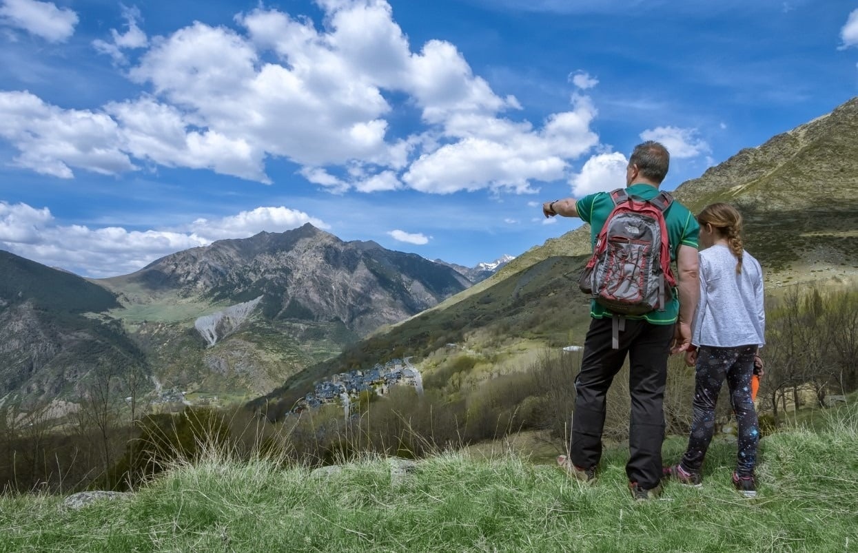 Aventura familiar: padre e hija explorando montañas con vistas impresionantes.