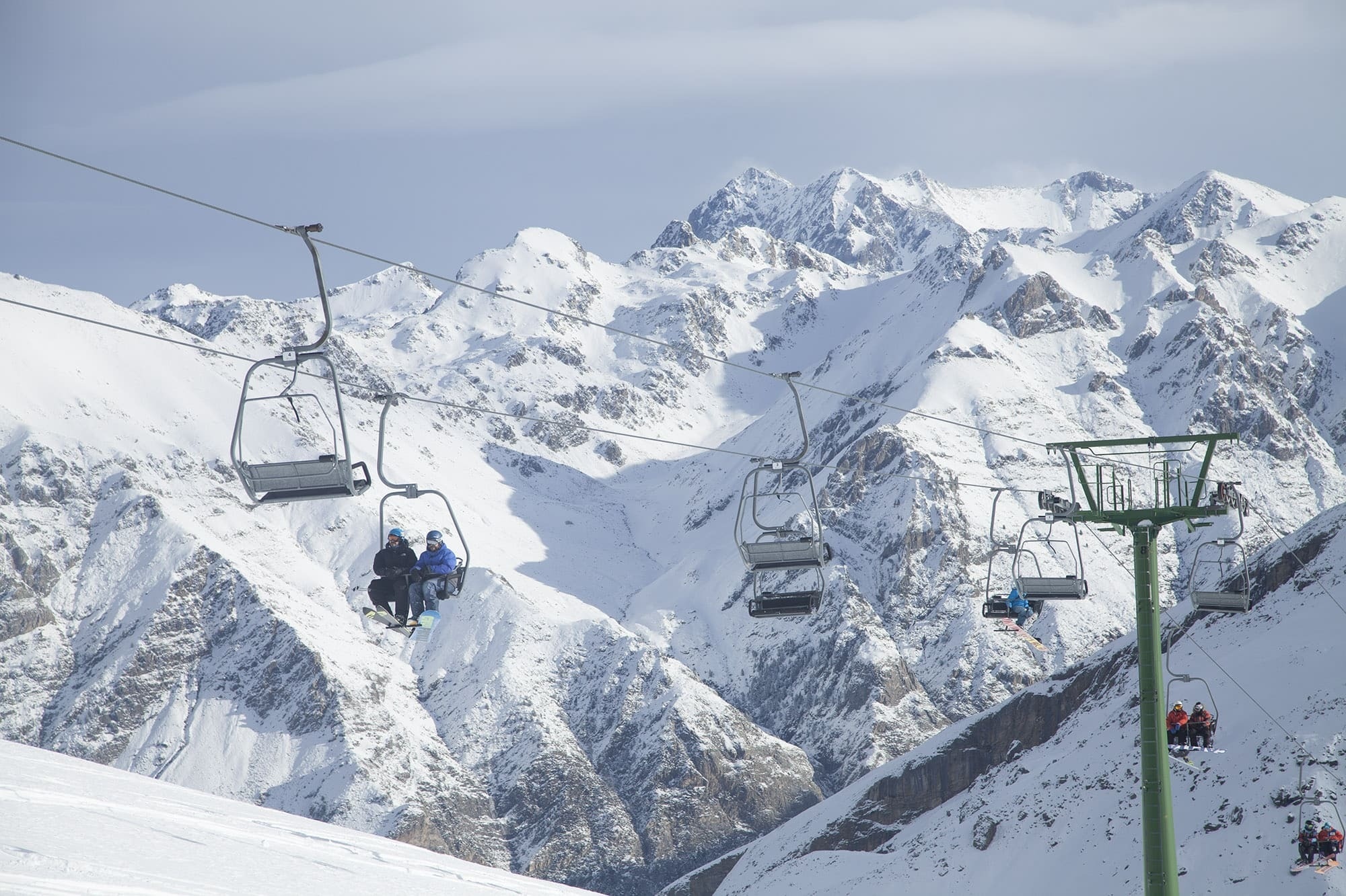 un teleférico en una estación de esquí con montañas cubiertas de nieve en el fondo