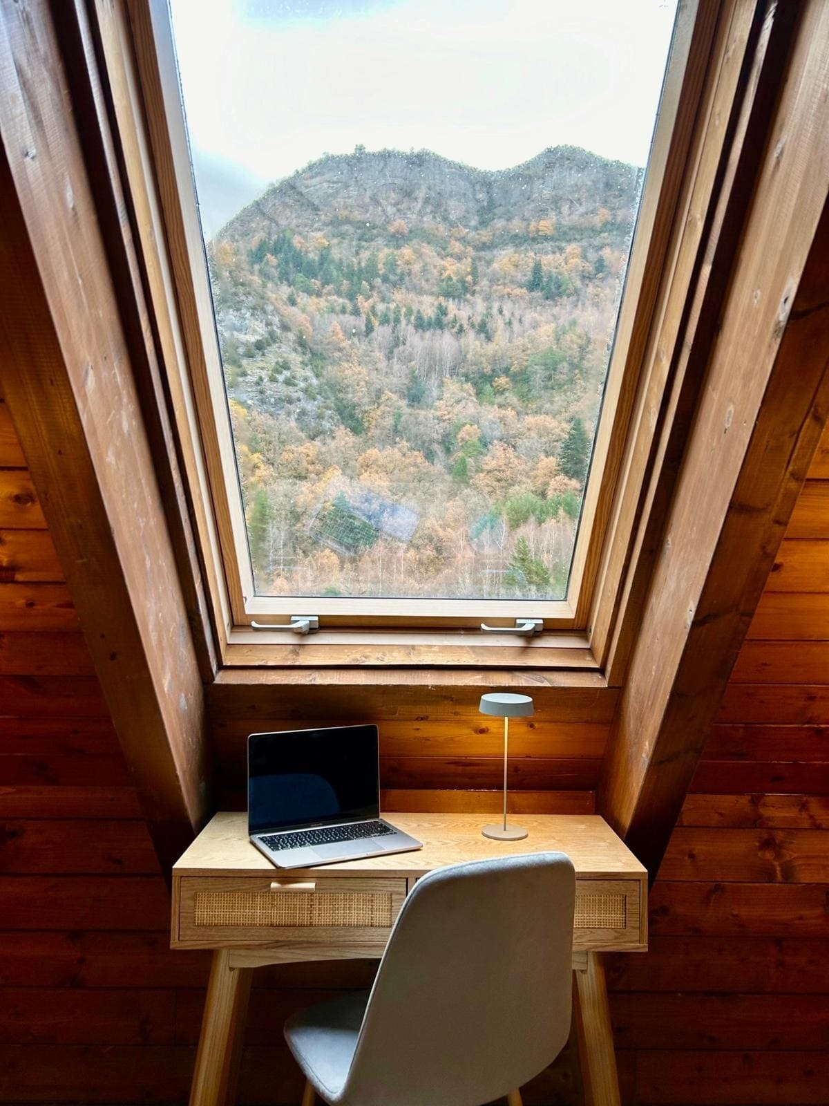 un bureau avec un ordinateur portable assis devant une fenêtre avec vue sur les montagnes