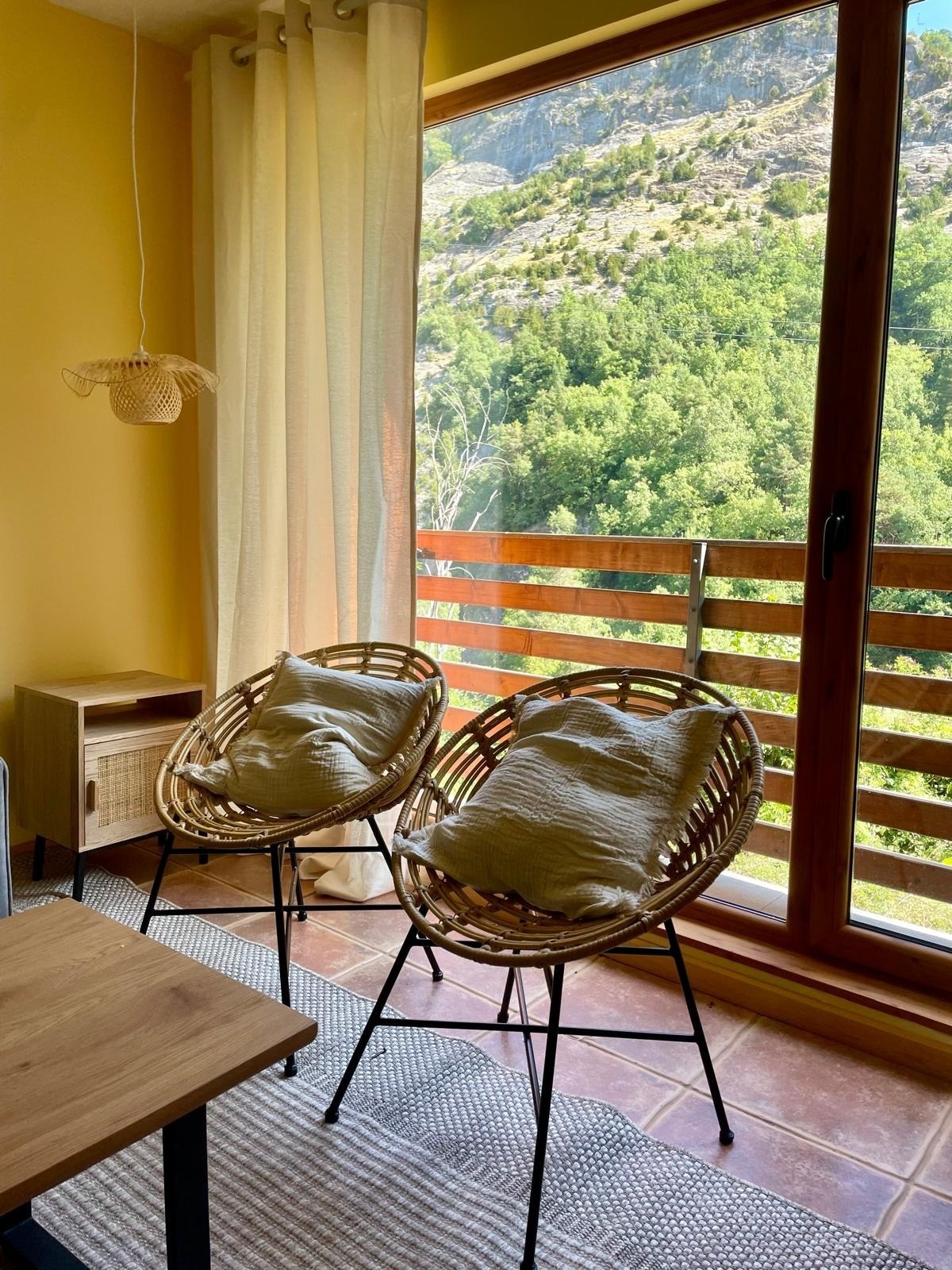 dos sillas de mimbre frente a una ventana con vista a un bosque