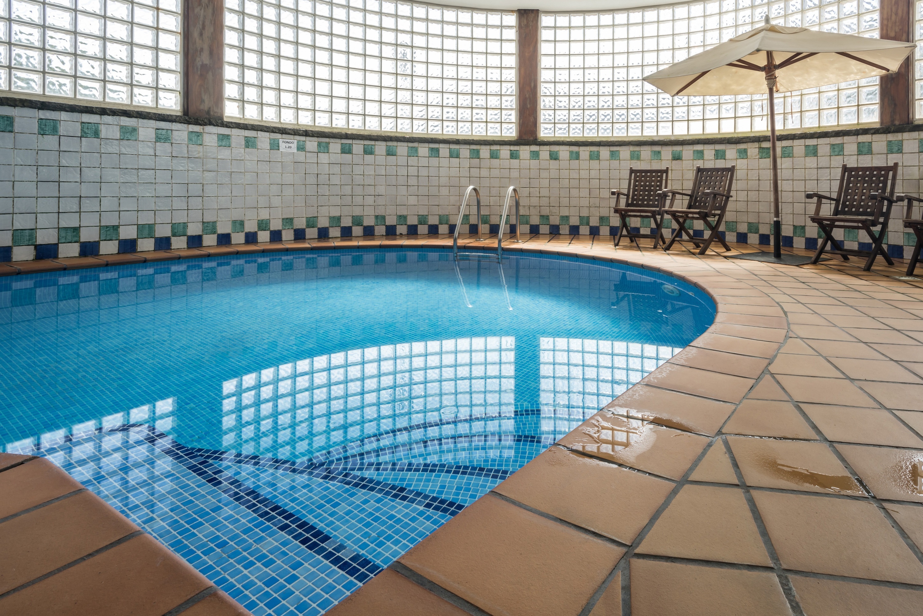 a large indoor swimming pool with chairs and an umbrella