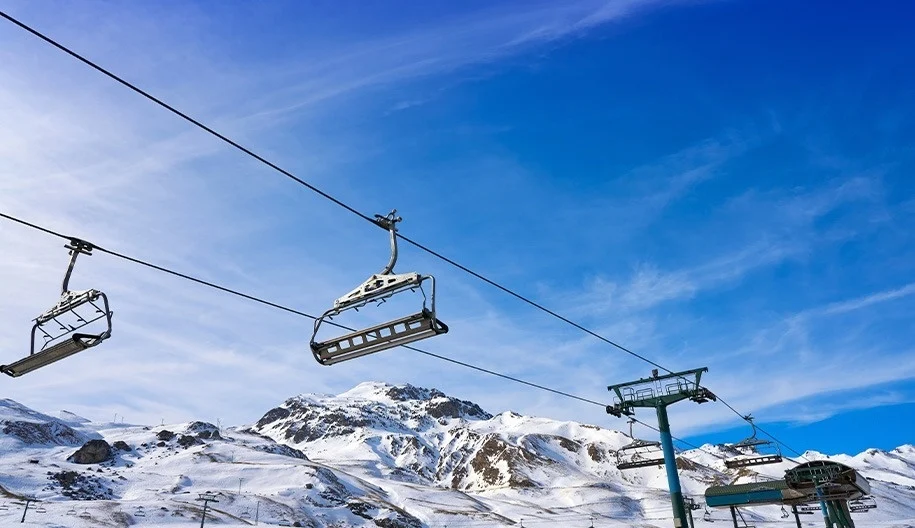 un teleférico en una estación de esquí con montañas cubiertas de nieve en el fondo