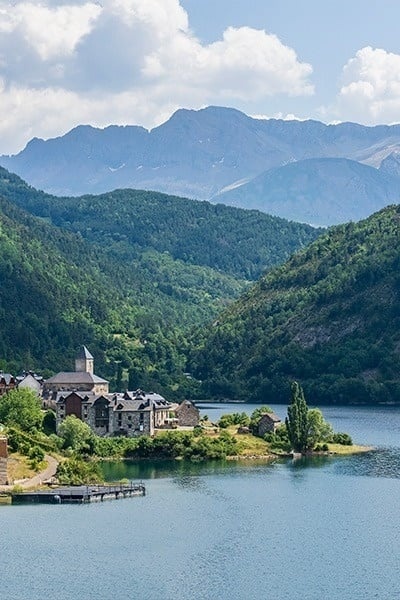 un pequeño pueblo en la ladera de una montaña junto a un lago al atardecer
