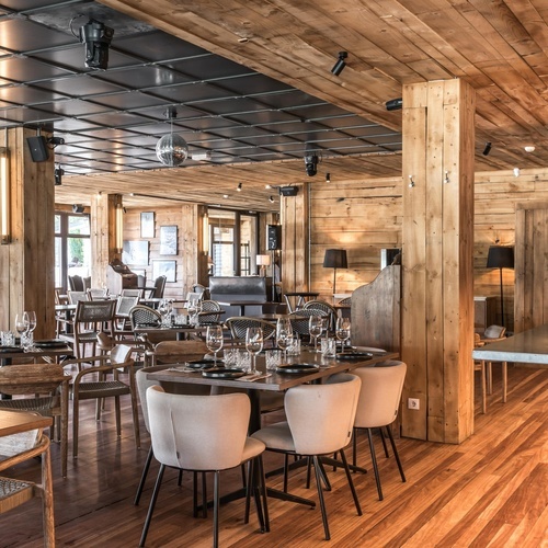 a restaurant with wooden tables and chairs and a red exit sign