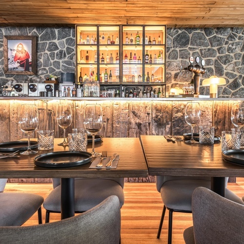 une salle à manger avec des tables et des chaises et un mur en pierre