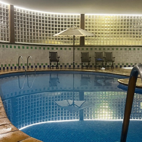 una piscina con un paraguas y sillas alrededor