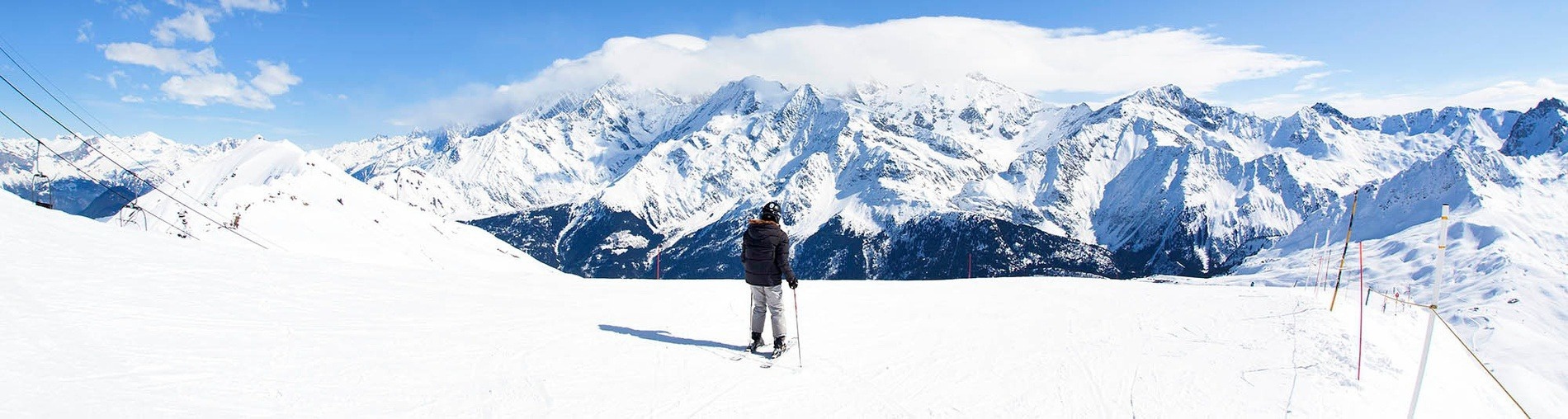 un hombre con esquís se para en la nieve mirando las montañas cubiertas de nieve