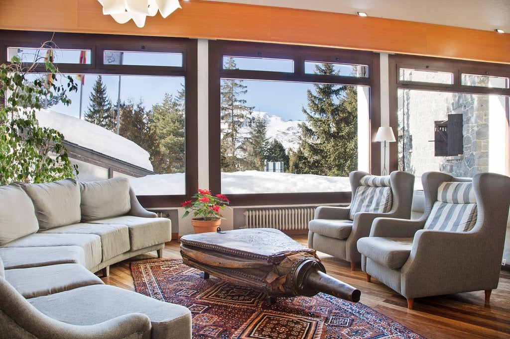 Lobby elegante del hotel SNO: Formigal con sofás, sillones y vista a la montaña.