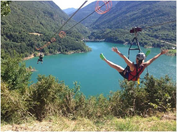 a woman is flying through the air on a zip line over a lake