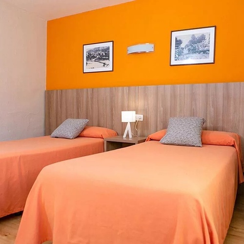 une chambre avec deux lits et un mur orange