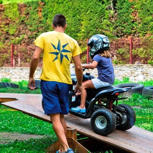 un hombre con una camiseta amarilla con una estrella en la espalda ayuda a una niña a montar un atv