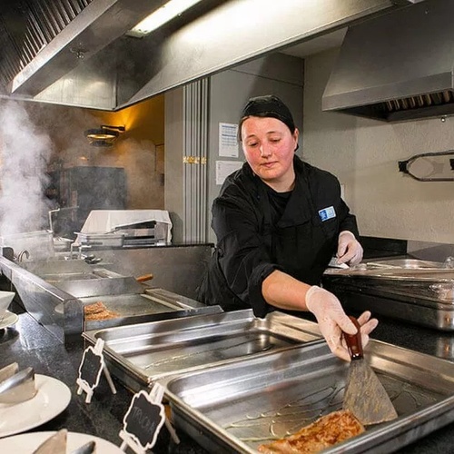 une femme prépare de la nourriture dans une cuisine avec une spatule