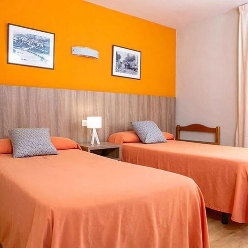 une chambre avec deux lits et un mur orange